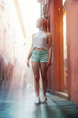 Pretty girl posing in Bologna street, Italy. Attractive model on the background of narrow ancient houses. Summer day. Urban. Travel and tourism. Vertical photo