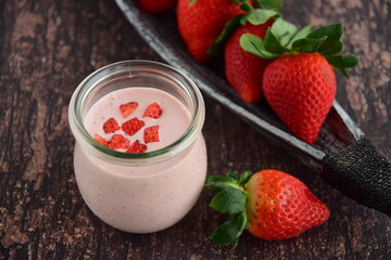 Fresh organic strawberry smoothie in a jar on wooden background