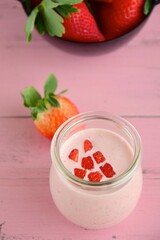Fresh strawberry yogurt smoothie in a jar on pink background