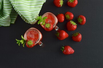 Fresh organic strawberry smoothie with mint in glass jar on black background