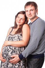 Portrait of Pregnant Caucasian Woman with Husband Standing Together Embraced.Against White.