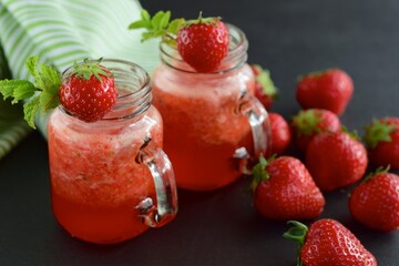 Fresh organic strawberry smoothie with mint in glass jar on black background