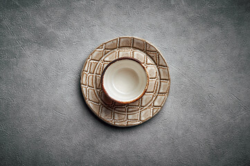 Blank ceramic saucer and plate like a crocodile skin texture on a dark background, copy space, top view