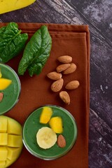 Spirulina green smoothie with banana, spinach, mango and almond nuts. Flat lay