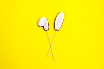 Easter cookie as bunny ears on a yellow background.