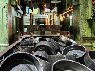 pile of stamped thick sheet black metal round parts after a hood operation in front of forming...