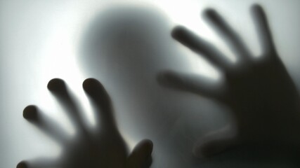 Silhouette of Man Behind Translucent Glass Touching the Surface with Both Hands