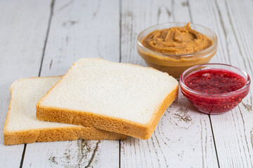 bread, jam and peanut butter on a light background