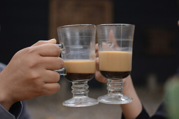 Male and female hands holding capuccino coffee drinks to toast together