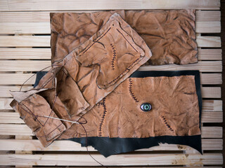 Leather pouch made of fresh zombie skin with green bloody eye and scars stitched with dark brown...