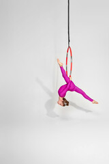 little child girl gymnast in pink sportwear doing twine on an aerial hoop © Rychko Yevhen