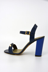 One thing, one pair of female blue lacquer sandals on a wide heel with a golden insole located on a white background. 