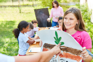 Girl in summer camp with drawing of a plant