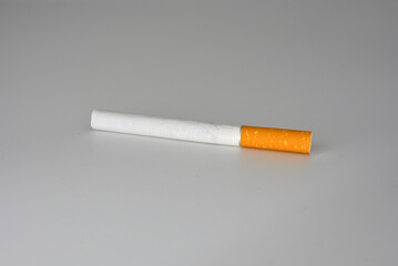 One white cigarette with brown filter located on a white background. Smoking is blicking bad on...