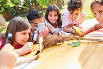 Inquisitive children look at tree bark with magnifying glasses