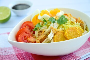 Soto Ayam, Indonesian food, yellow spicy chicken soup with vermicelli, fried potato, hard boiled egg and fried shallot.