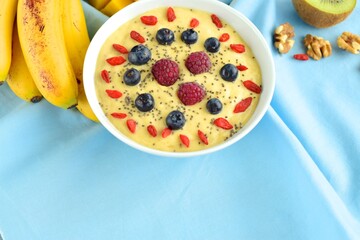 Mango banana pineapple smoothie bowl topped with raspberry, blueberry, goji berry and chia seeds
