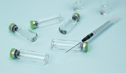 the syringe is lying on the ampoule with the vaccine. the syringe is in focus, the ampoules in the background are blurred. vaccination against coronavirus.