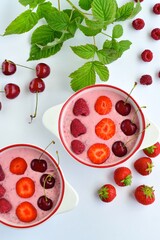 Breakfast berry smoothie bowl topped with raspberry, strawberry and cherry on white background