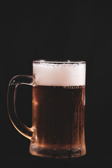 a pint full of beer and foam on a black background. alcoholic soft drink
