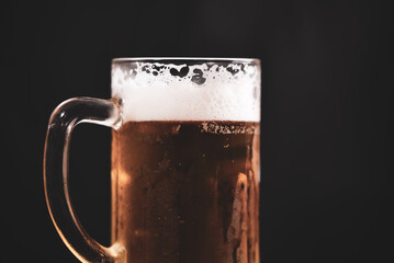 a pint full of beer and foam on a black background. alcoholic soft drink
