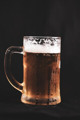 a pint full of beer and foam on a black background. alcoholic soft drink
