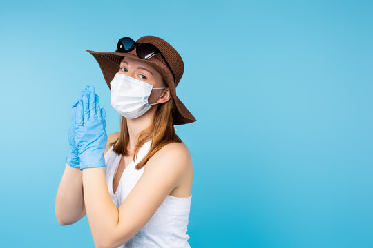 A tourist in summer clothes and protective equipment. Medical mask and protective gloves praying on a blue background with side space. Pandemic fatigue.
