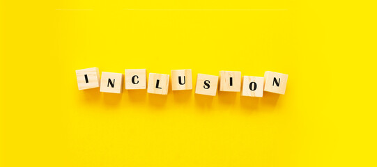 Inclusion concept banner word on wooden cubes on yellow background
