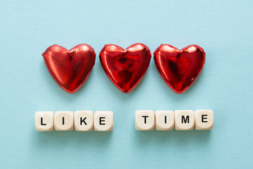 Like time words, made of wooden letters with red heart on blue background. Social media concept.