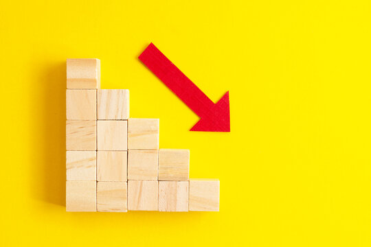 Business decrease concept abstract yellow background. Red arrow and wooden stairs.