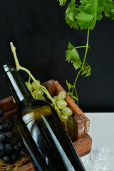 A bunch of grapes and a wine bottle on a white table, close up