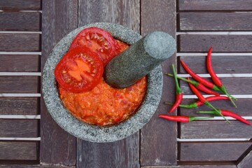 Homemade sambal tomat (spicy tomato sambal) in mortar and pestle on wooden table