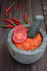 Homemade sambal tomat (spicy tomato sambal) in mortar and pestle on wooden table