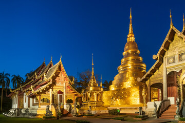 Fototapeta premium Chapel and golden pagoda at Wat Phra Singh Woramahawihan in Chiang Mai at twilight or night with stars in sky