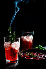 Amazing composition with strawberry cheesecake and strawberry drink with rosemary. Only part of the cheesecake in focus and a particle of a glass of drink.
