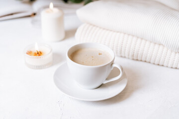 Details of still life in the home interior of living room. Cup of coffee, cotton, book, candle, sweater. Moody. Cosy autumn winter concept on white background. Decoration.