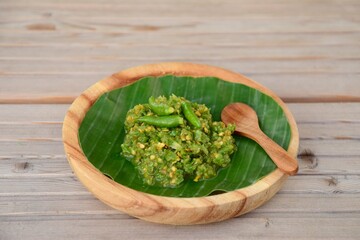 Sambal Cabe Ijo. Traditional Indonesian green chili paste on banana leaf, place on wooden background