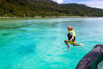 Child jumping into sea water. Yacht vacation.