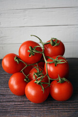 Red tomatoes on a branch on a wooden background.