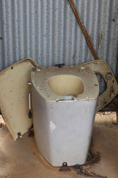 broken dirty unused outdoor toilet in tin shed