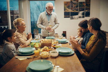 Happy senior man holding a toast during family lunch at home.