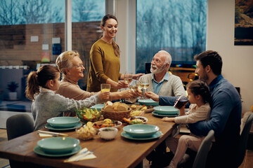 Happy multi-generation family toasting during a meal at dining table.