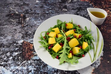 Arugula salad with mango and pomegranate served with Vinaigrette dressing