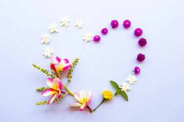 purple globe amaranth, jasmine, frangipani and marigold flowers arrangement flat lay postcard heart style on background white