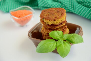 Patties of red lentils with basil leaf on white background