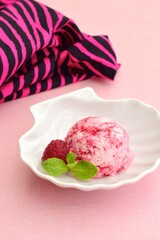 One scoop of raspberry ice cream with mint leaf. Pink background