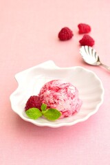 One scoop of raspberry ice cream with mint leaf. Pink background