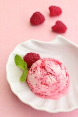 One scoop of raspberry ice cream with mint leaf. Pink background