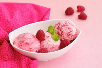 Scoops of raspberry ice cream in a bowl garnish with mint leaves. Summer dessert