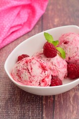 Scoops of raspberry ice cream in a bowl garnish with mint leaves. Summer dessert